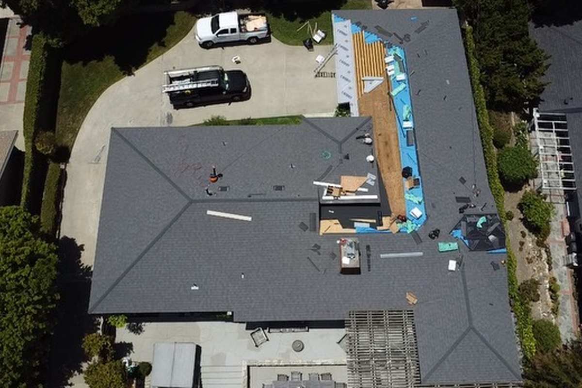 Roof-level photograph showing a shingle roof with an active work area seen from directly above.