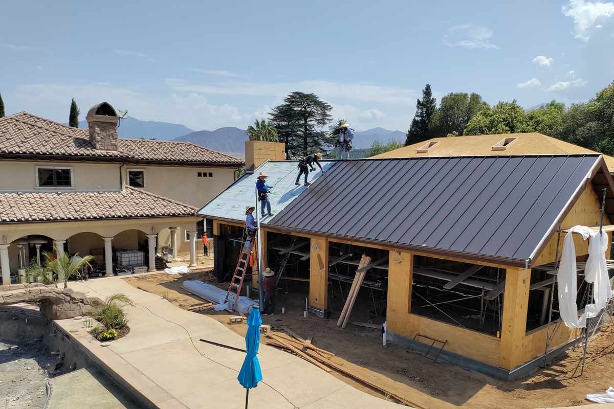 Roof-level photograph showing a metal roof beside an exposed wood roof deck.