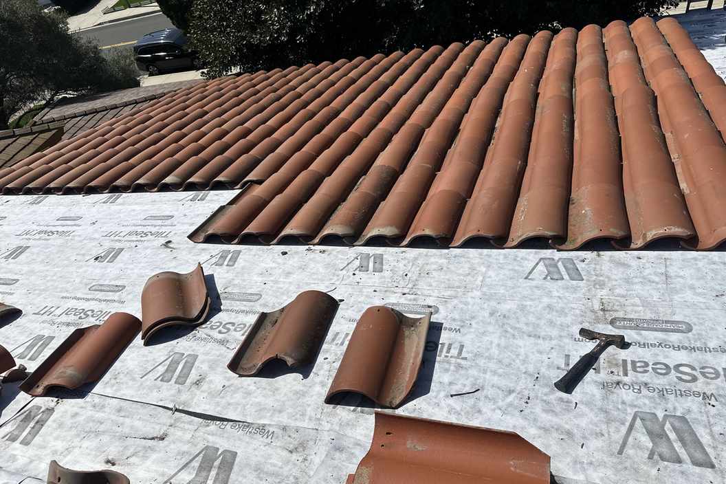 Daylight view of clay roof tiles staged over underlayment.