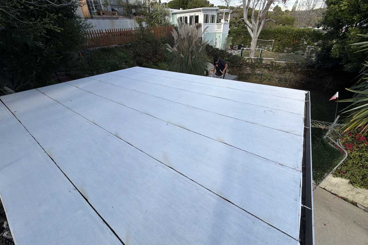 Daylight view of a pale low-slope roof field with long parallel seams.