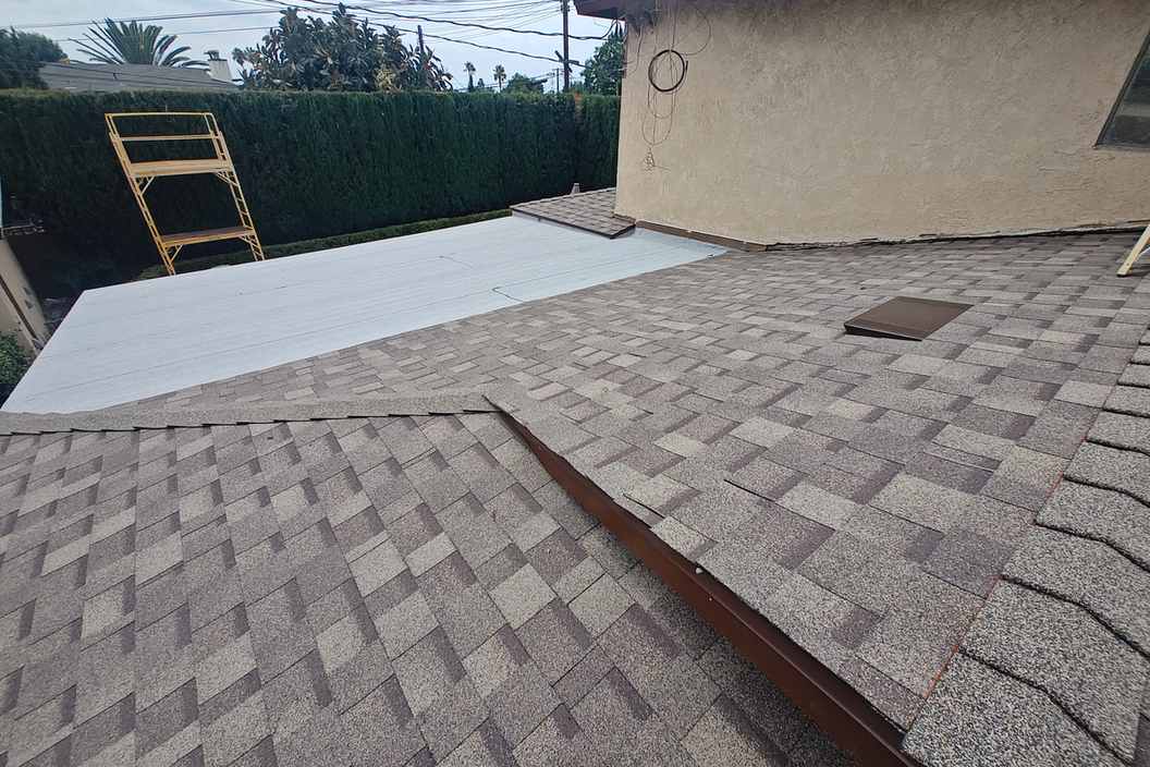 Daylight view of a shingle roof meeting a pale low-slope section.