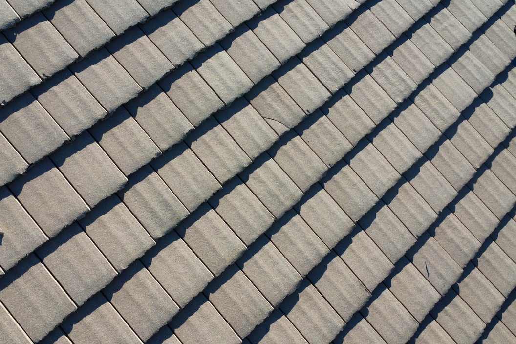 Roof-level photograph showing rows of flat concrete roof tiles viewed close up.